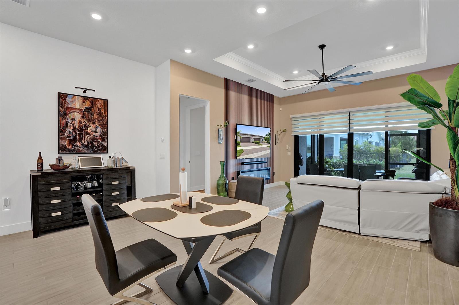 A dining area with a modern table and chairs sits before a living room space — 8334 W Blue Spring Drive # 8334, Parkland FL 33067, PARKLAND, FL