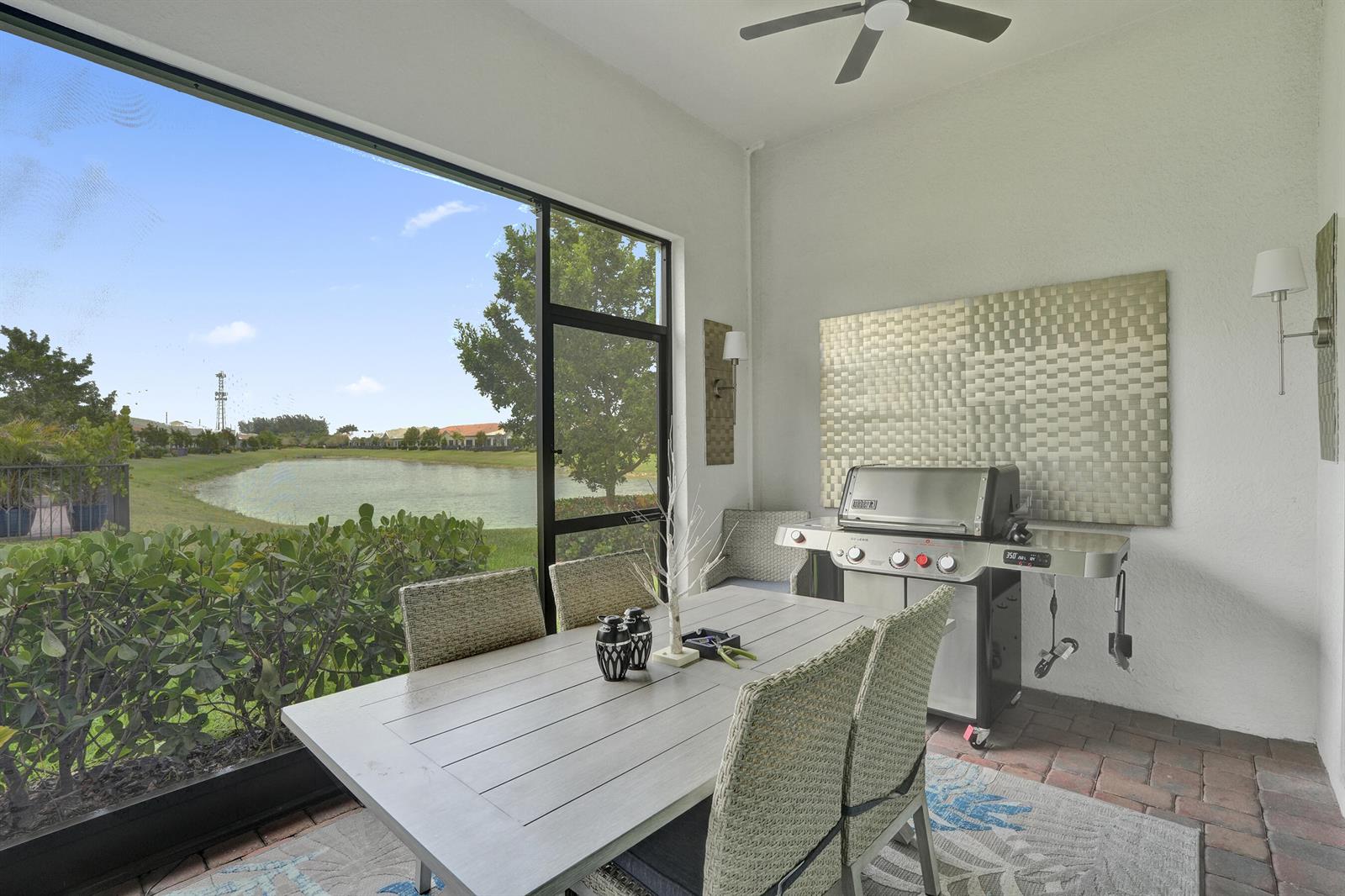 A covered patio features a dining set, a grill, and a view of a lake — 8334 W Blue Spring Drive # 8334, Parkland FL 33067, PARKLAND, FL