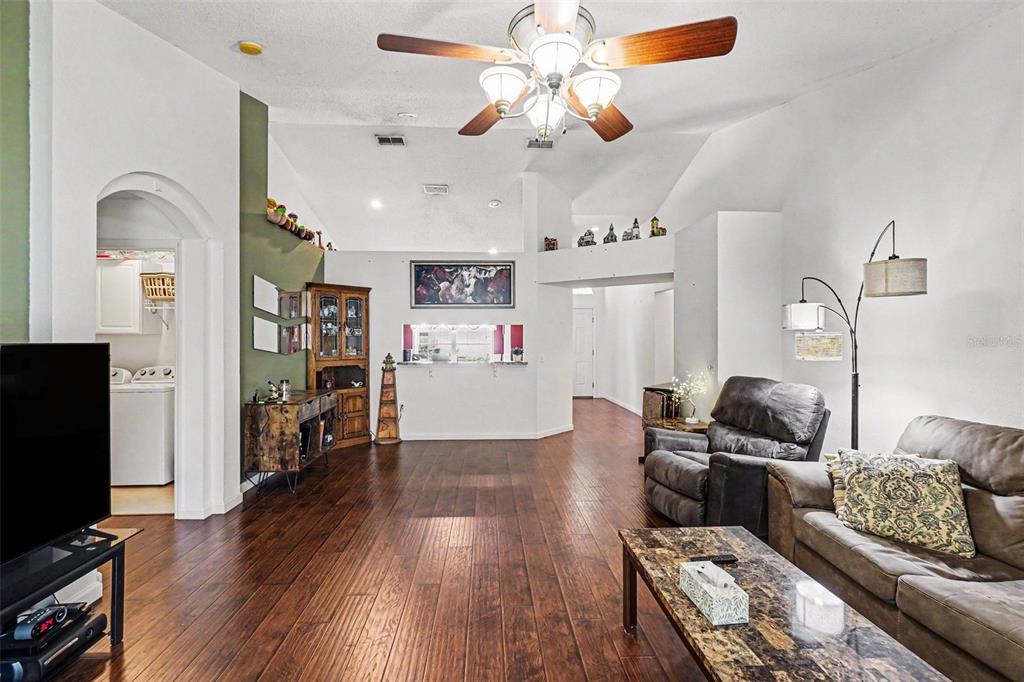 A living room with dark wood flooring, a ceiling fan, and a pass-through kitchen window — 531 HEATHER GLEN DRIVE, WINTER HAVEN, FL