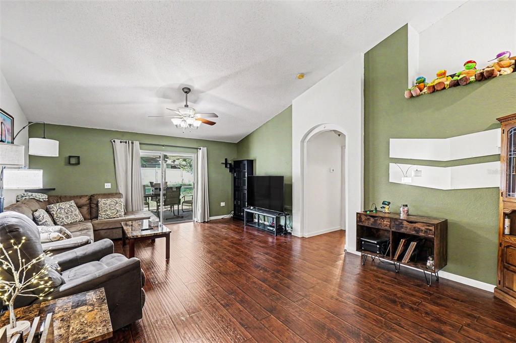 A living room features green walls, wood-look flooring, a vaulted ceiling, and a sliding glass door — 531 HEATHER GLEN DRIVE, WINTER HAVEN, FL