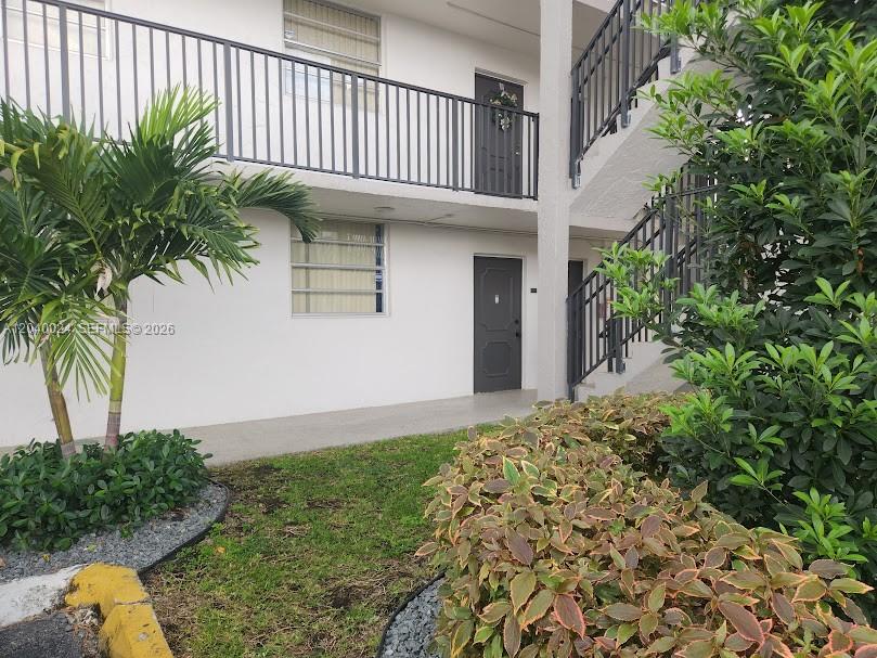 An exterior view of a two-story apartment building with stairs and a palm tree — 14185 SW 87th St # A110, Miami FL 33183, MIAMI, FL