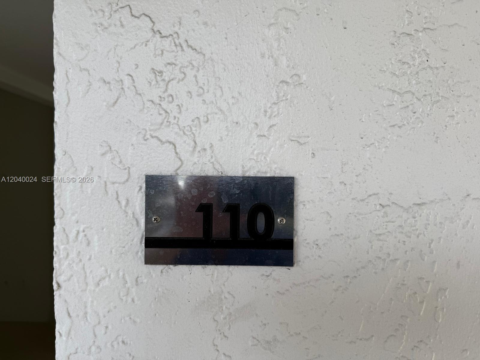 A metal sign with the number 110 is mounted on a textured white wall — 14185 SW 87th St # A110, Miami FL 33183, MIAMI, FL