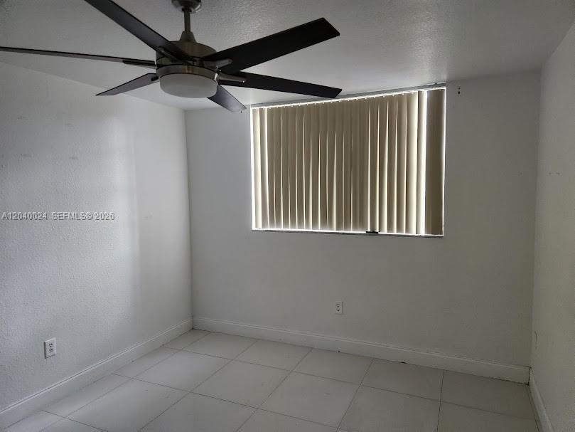 An empty bedroom features white walls, tiled floors, a ceiling fan, and vertical window blinds — 14185 SW 87th St # A110, Miami FL 33183, MIAMI, FL