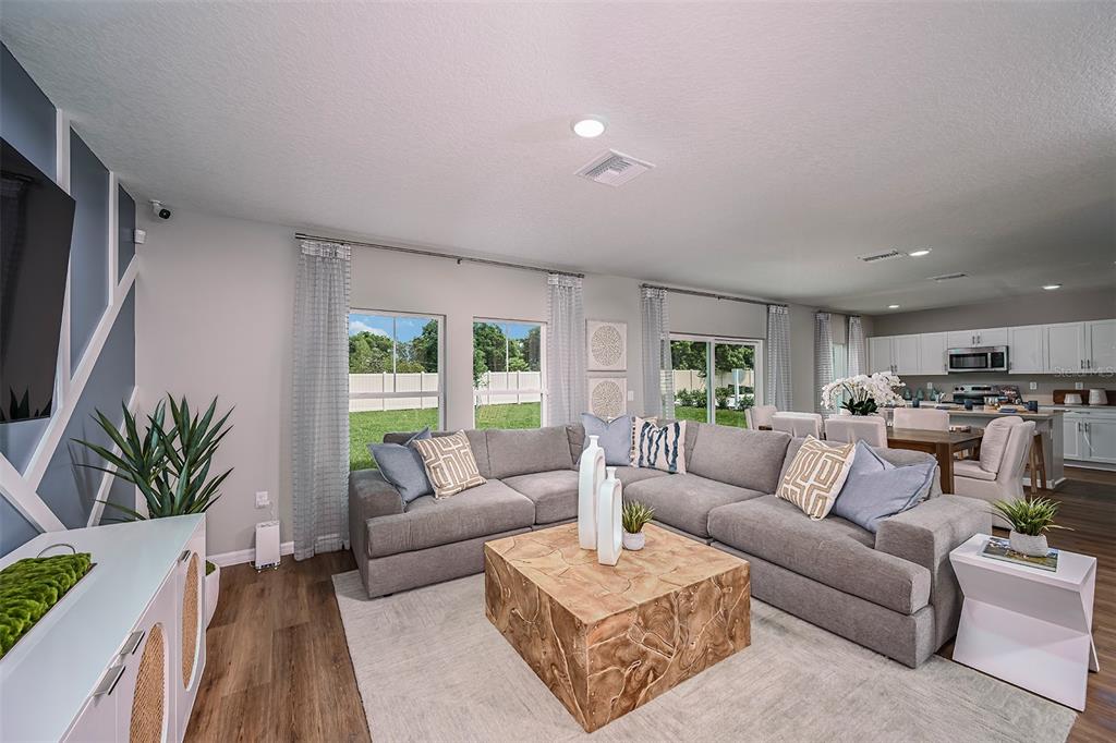A living room features a gray sectional sofa, a wooden coffee table, and an open kitchen — 1760 VANILLA STREET, LAKE HAMILTON, FL