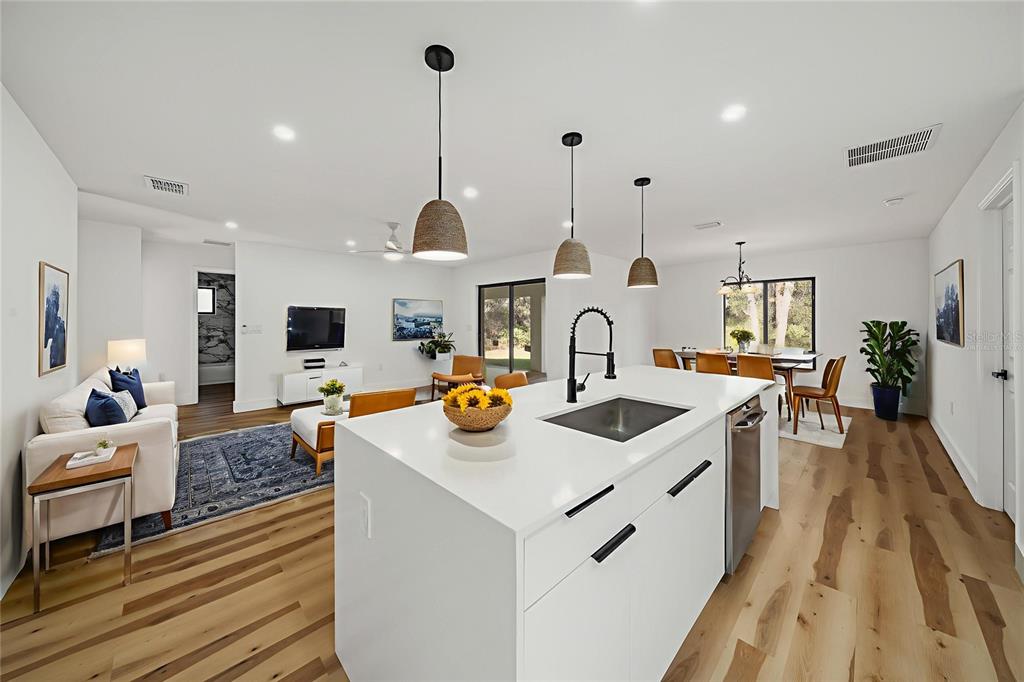 A modern open-concept kitchen and living area featuring a white island and hardwood floors — 15460 CHAMBERLAIN BOULEVARD, PORT CHARLOTTE, FL