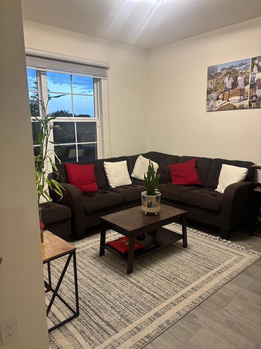 A living room features a dark sectional sofa, a coffee table, and a patterned area rug — 1598 Leeward Avenue SE, Palm Bay FL 32909, PALM BAY, FL