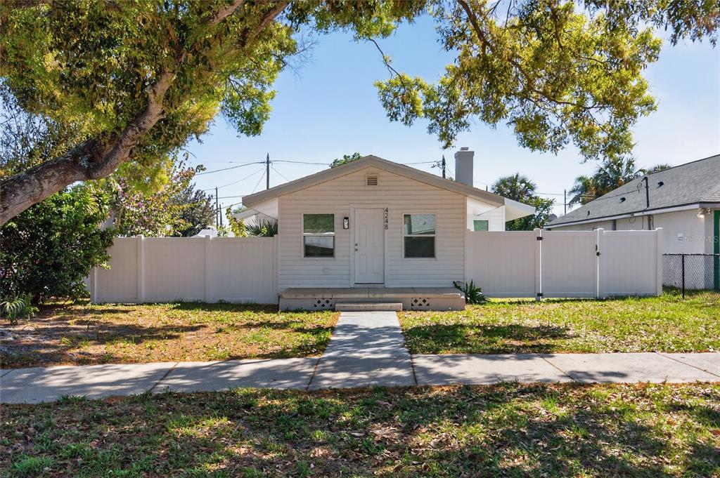 A living room with light wood floors, a black fireplace, and a white exterior door — 4248 4TH AVENUE S, ST PETERSBURG, FL