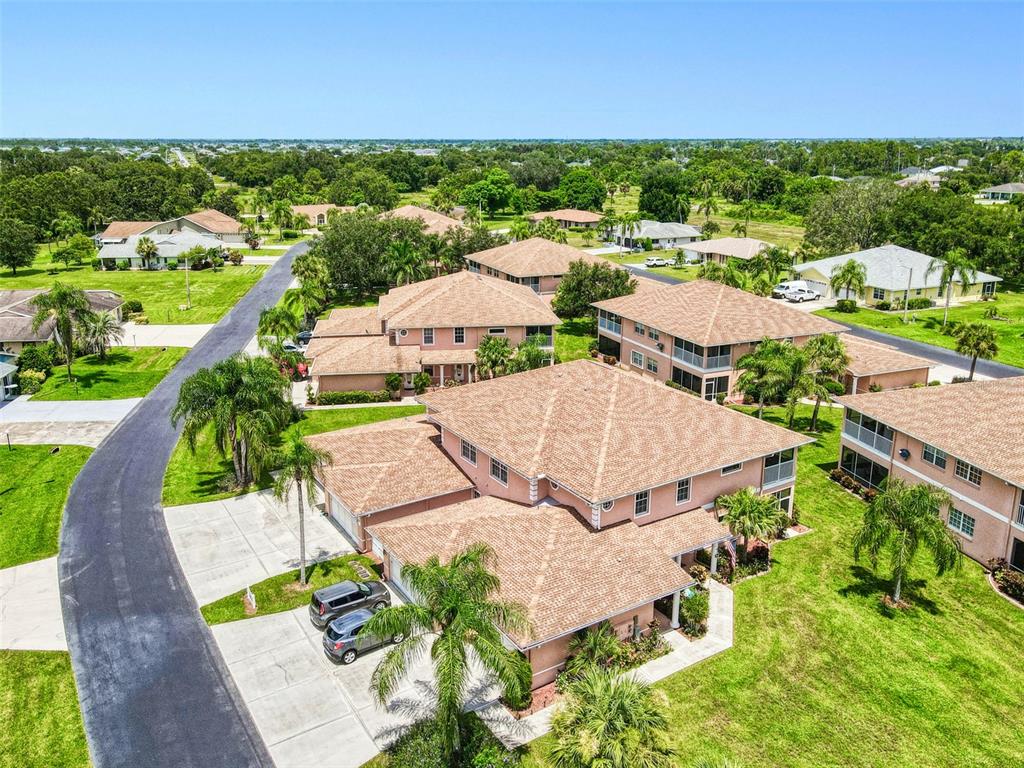 An aerial view shows a multi-story residential building with a tan roof and parking area — 19977 LAKE VISTA CIRCLE UNIT 17D, LEHIGH ACRES, FL