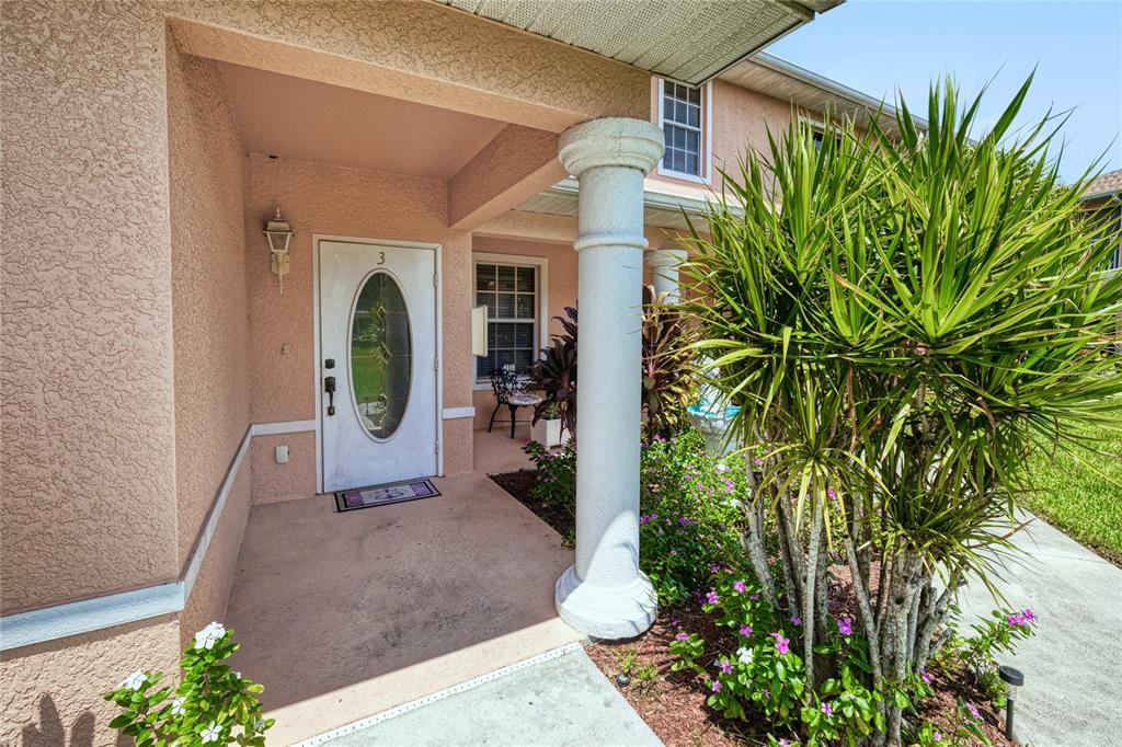 A covered entryway features a white front door with an oval window and a stone column — 19977 LAKE VISTA CIRCLE UNIT 17D, LEHIGH ACRES, FL