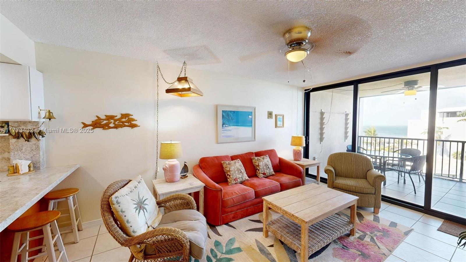 A living room features a red sofa, wicker chair, coffee table, and a balcony with ocean views — 104350 Overseas Highway # 402, Key Largo FL 33037, KEY LARGO, FL