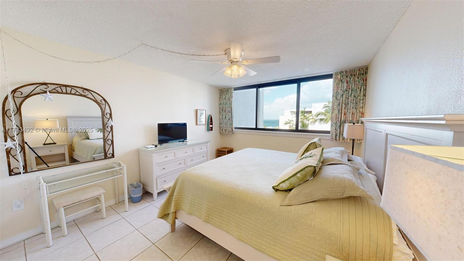 A bedroom features a bed, a dresser with a television, and a large arched mirror — 104350 Overseas Highway # 402, Key Largo FL 33037, KEY LARGO, FL