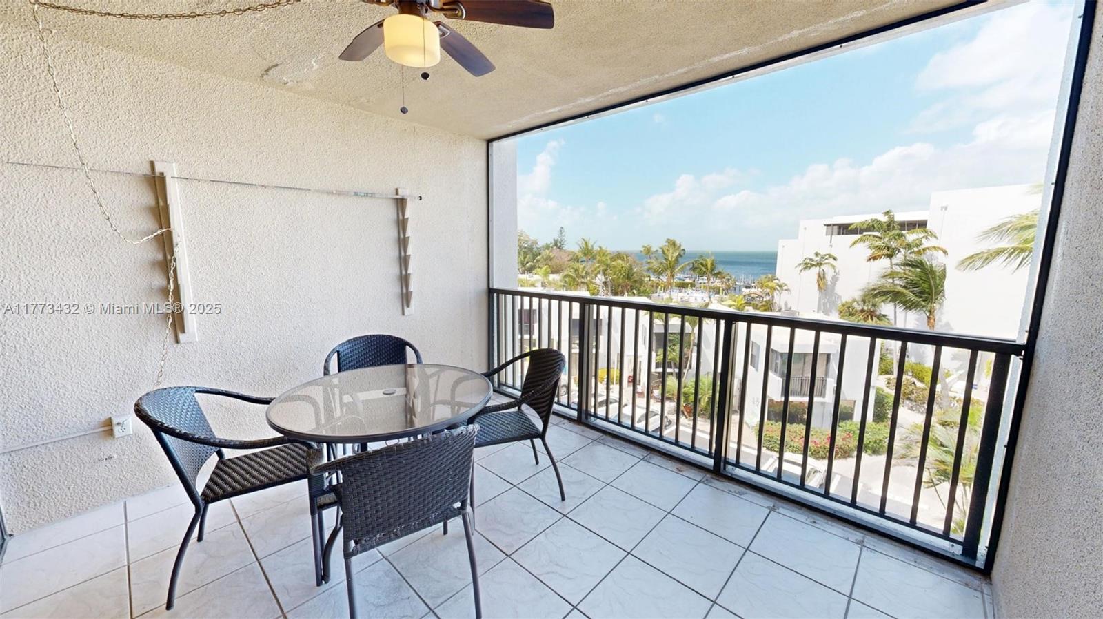 A balcony with a glass-top table, four chairs, a ceiling fan, and a water view — 104350 Overseas Highway # 402, Key Largo FL 33037, KEY LARGO, FL