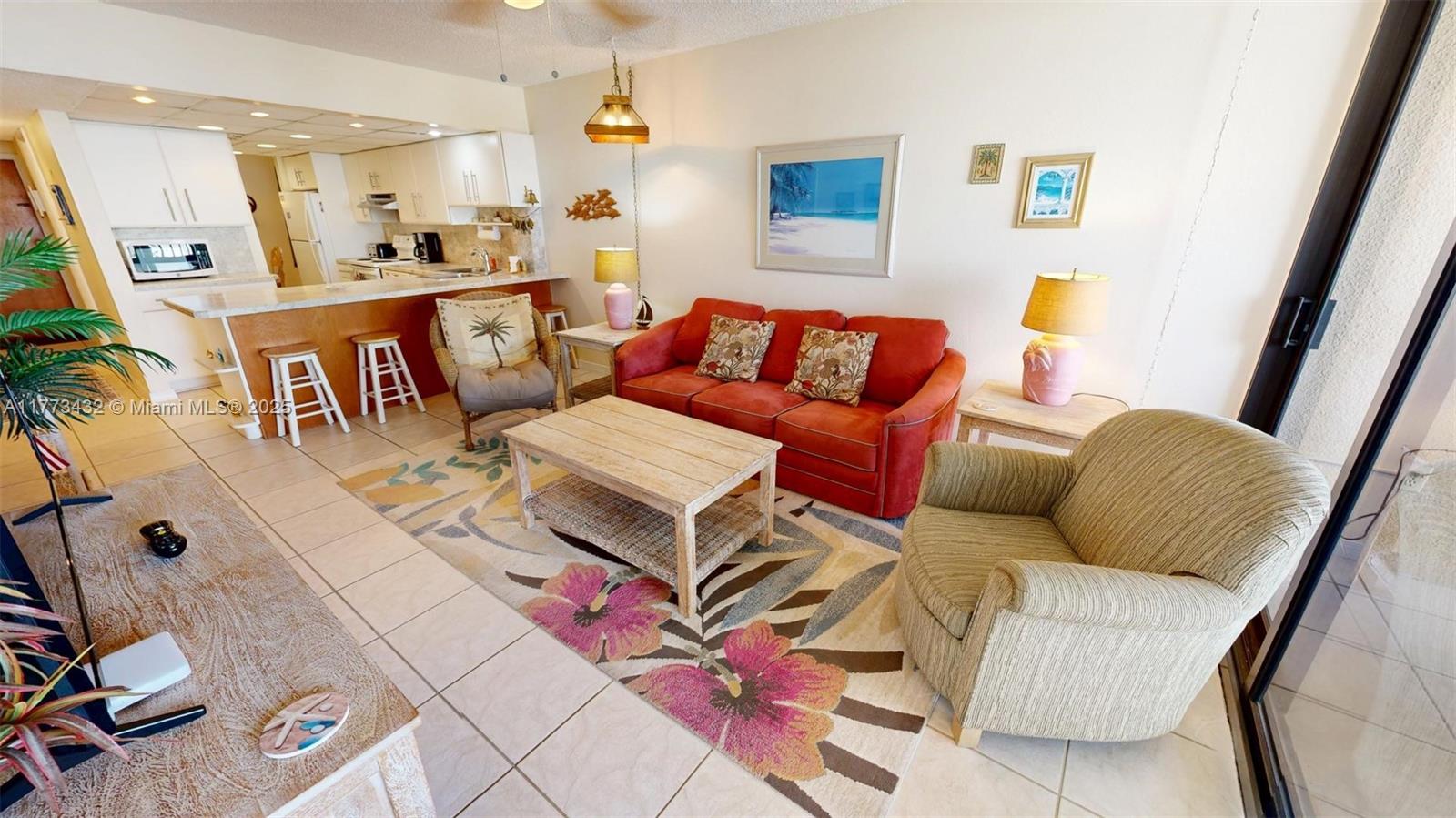 A living room with a red sofa, patterned area rug, and an open kitchen area — 104350 Overseas Highway # 402, Key Largo FL 33037, KEY LARGO, FL