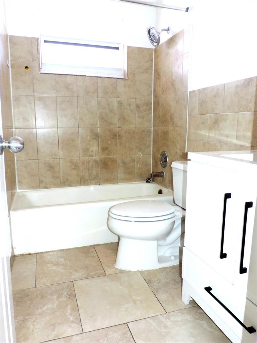 A bathroom features a white vanity, a toilet, and a bathtub with tan tiled walls — 1621 SW 6th Avenue # 2, Pompano Beach FL 33060, POMPANO BEACH, FL
