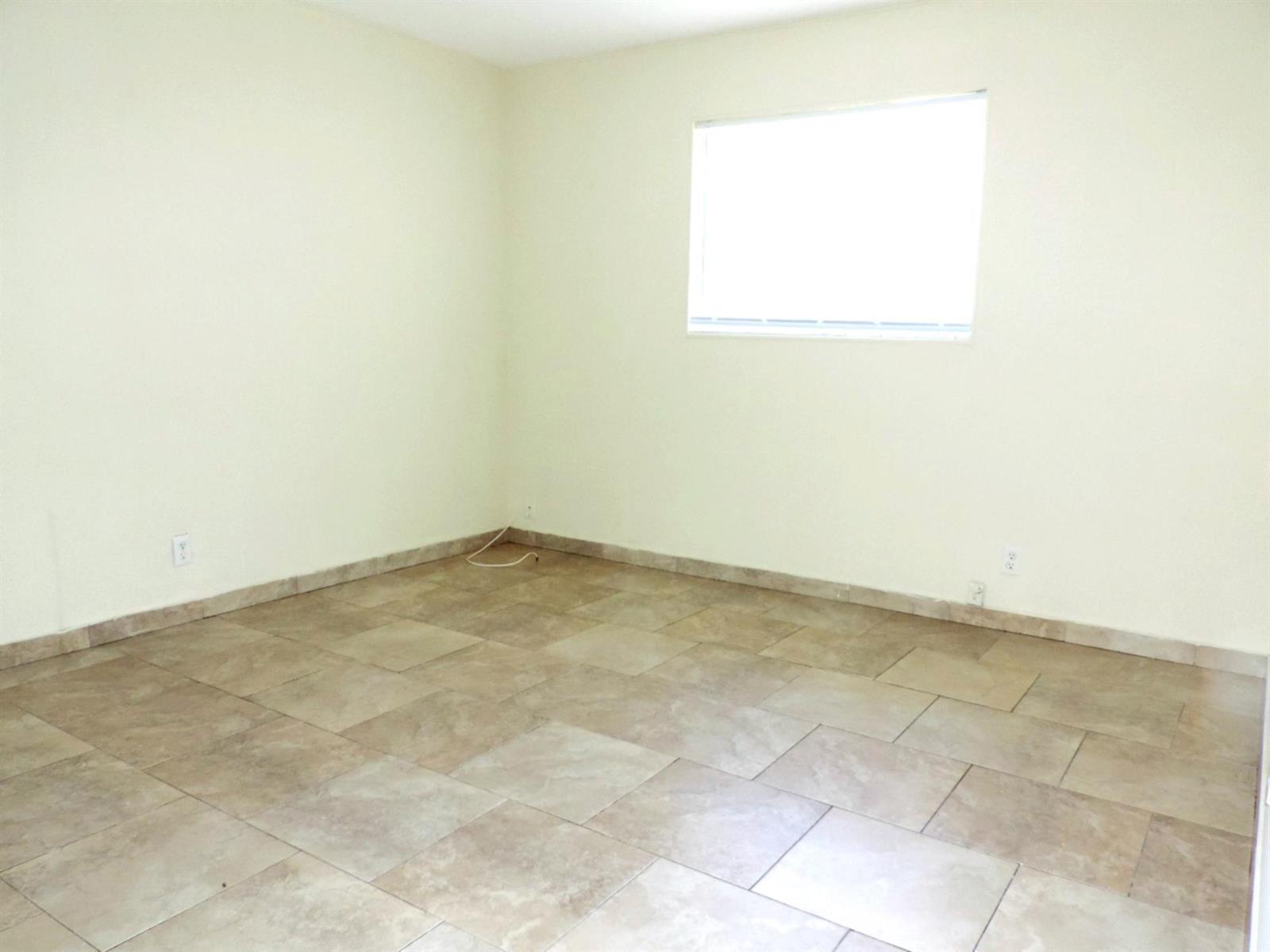 An empty room features light-colored walls, large square floor tiles, and a single window — 1621 SW 6th Avenue # 2, Pompano Beach FL 33060, POMPANO BEACH, FL