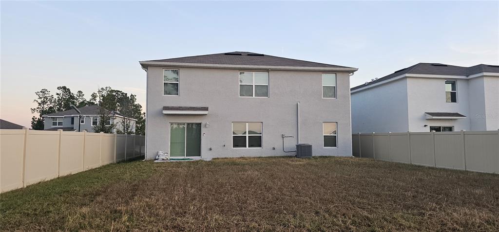 The rear exterior of a two-story house features a sliding glass door and fenced yard — 1220 TAHITIAN SUNRISE DRIVE, PLANT CITY, FL