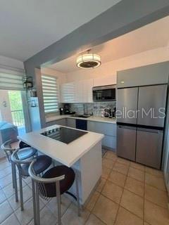 A modern kitchen features white cabinetry, stainless steel appliances, and a breakfast bar with stools — 1 HARBOUR LAKES UNIT 53, HUMACAO, PR