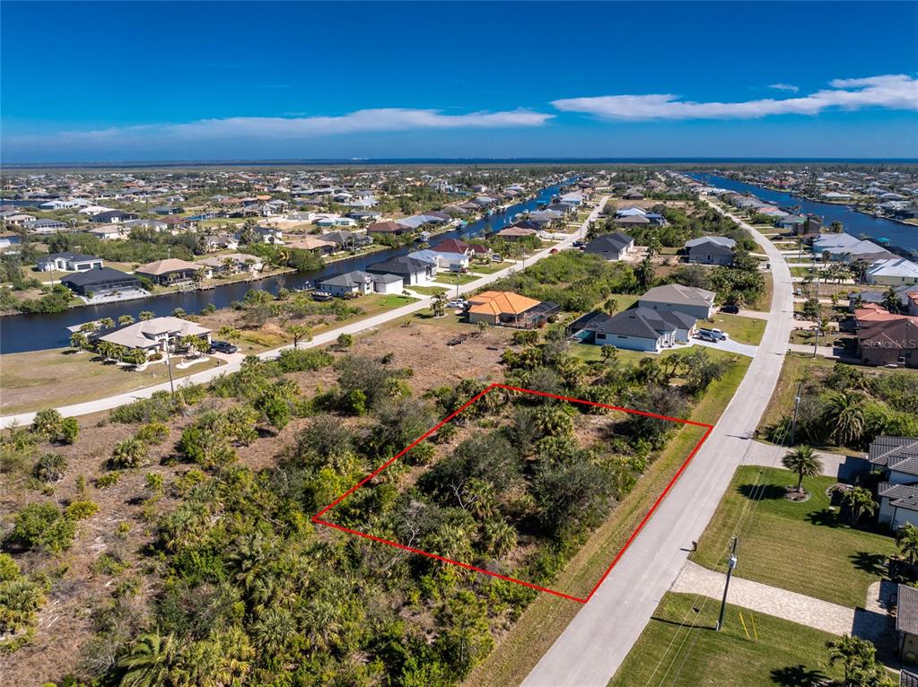 An aerial view shows a vacant, brush-covered residential lot outlined in red along a road — 15453 and 15461 ALSASK CIRCLE, PORT CHARLOTTE, FL