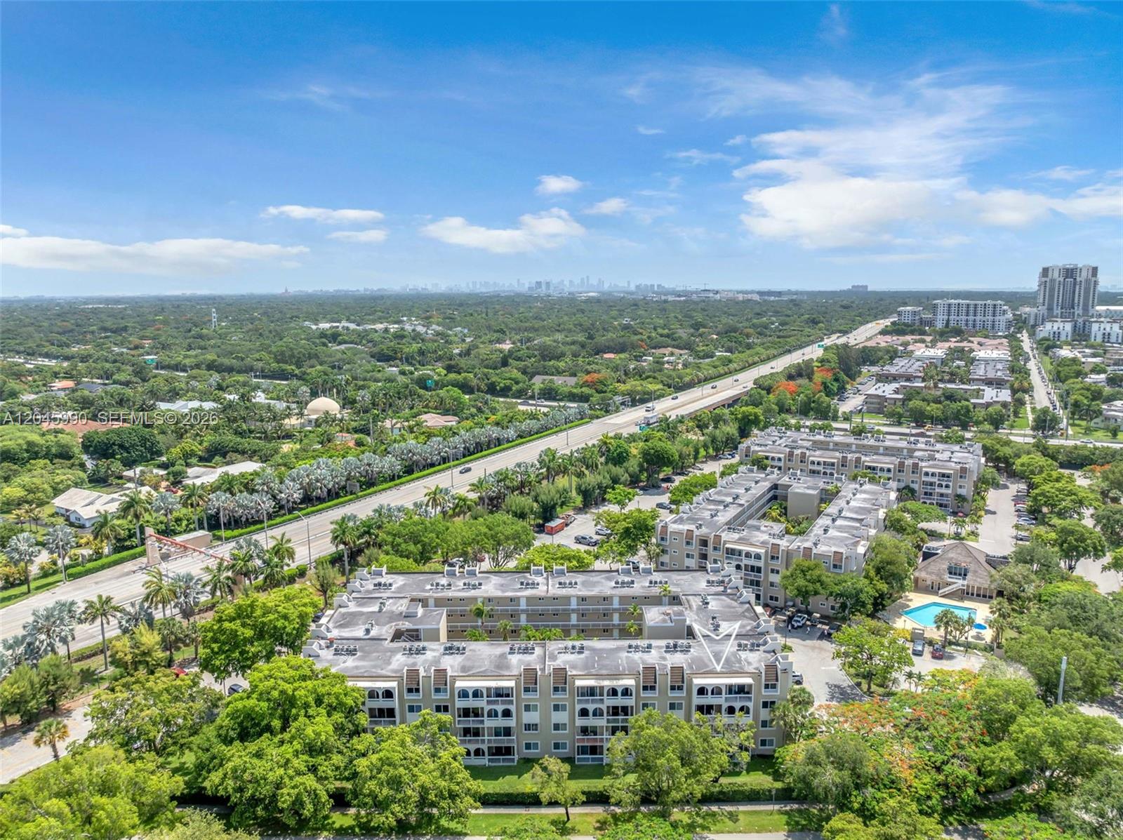 An aerial view shows a multi-story apartment complex with a pool and surrounding greenery — 8101 Camino Real # 402, Miami FL 33143, MIAMI, FL