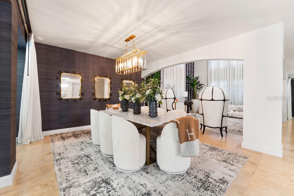 A dining room features a marble table, white chairs, a gold chandelier, and dark wallpaper — 386 DORADO BEACH EAST, DORADO, PR