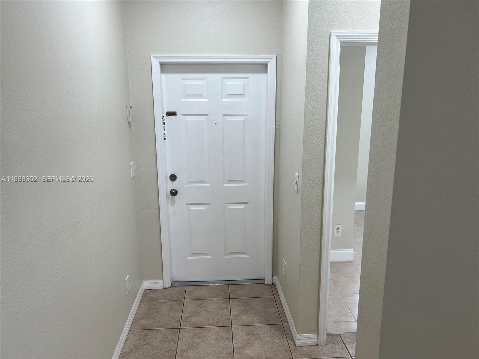 A white entry door with a security chain is centered in a tiled foyer — 85 SW 16 AV, Homestead FL 33030, HOMESTEAD, FL