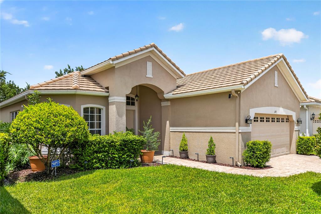 A single-story house with a beige stucco exterior, a tiled roof, and a two-car garage — 619 NEWHALL LANE, DEBARY, FL