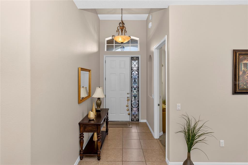 An entryway features tile flooring, a wooden console table, a chandelier, and a white front door — 619 NEWHALL LANE, DEBARY, FL