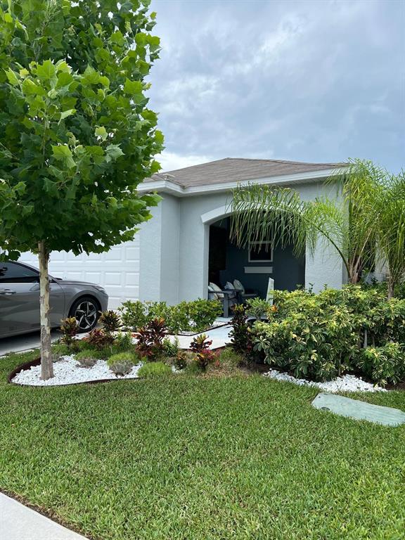A light-colored house exterior features a covered entryway, a driveway, and landscaped front yard — 7111 AMELIA COVE COURT, SUN CITY CENTER, FL