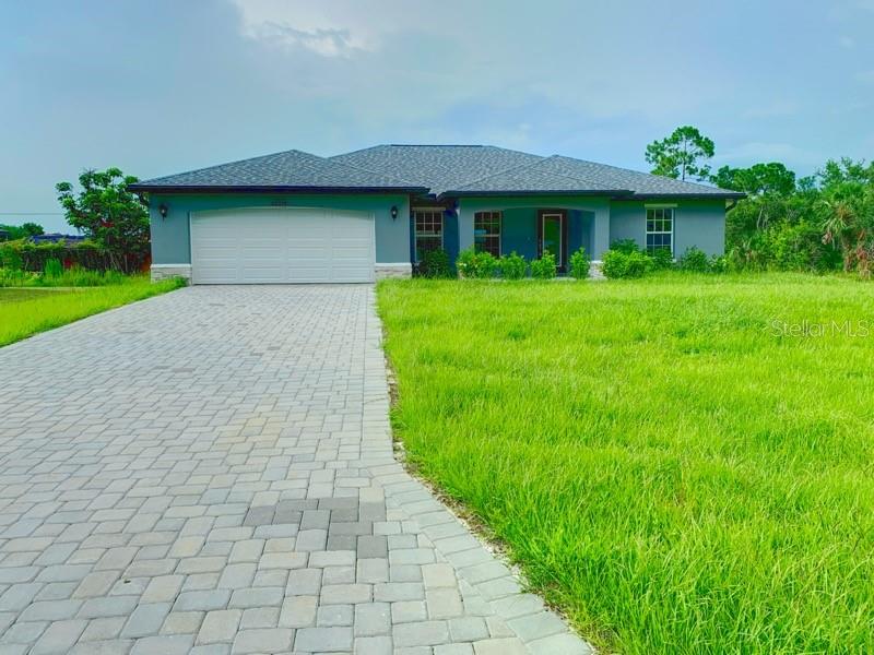 A single-story house with a paved driveway and a large grassy yard under a cloudy sky — 22376 BLANCHARD AVENUE, PORT CHARLOTTE, FL