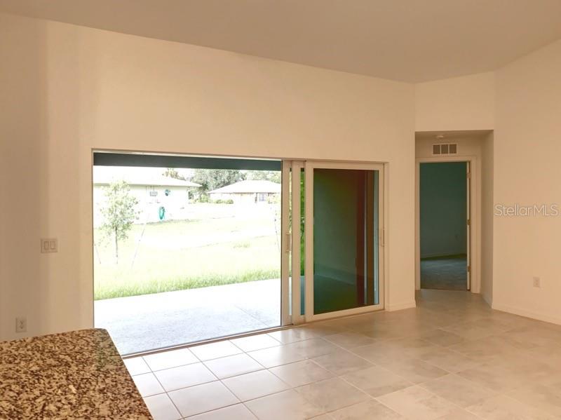A room with tile flooring, a granite countertop, and a sliding glass door to a patio — 22376 BLANCHARD AVENUE, PORT CHARLOTTE, FL
