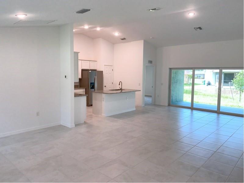 An open-concept kitchen with a center island and tile flooring overlooks a living area — 22376 BLANCHARD AVENUE, PORT CHARLOTTE, FL