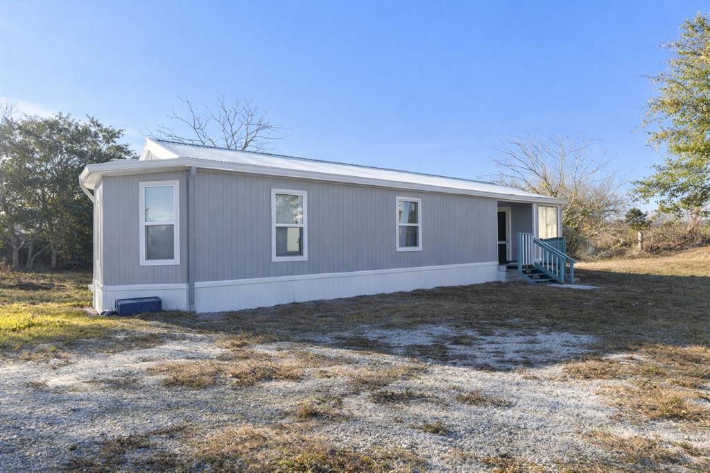 A single-story manufactured home with gray vertical siding and a white metal roof — 702 W HILLSBORO STREET, PLANT CITY, FL