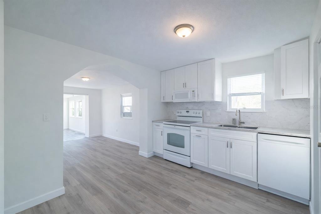 A bright kitchen features white cabinets, stainless steel appliances, and light wood-look flooring — 702 W HILLSBORO STREET, PLANT CITY, FL