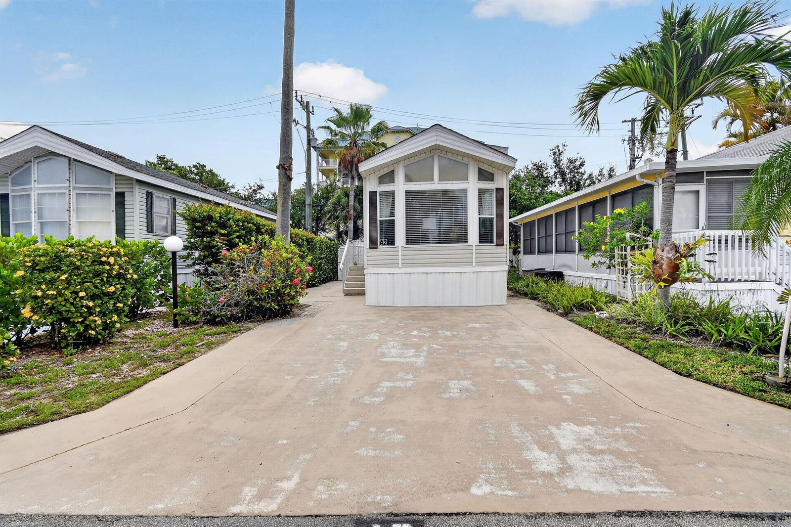 A mobile home with a concrete driveway and a palm tree in a residential park — 900 Juno Ocean Walk # 2, Juno Beach FL 33408, JUNO BEACH, FL
