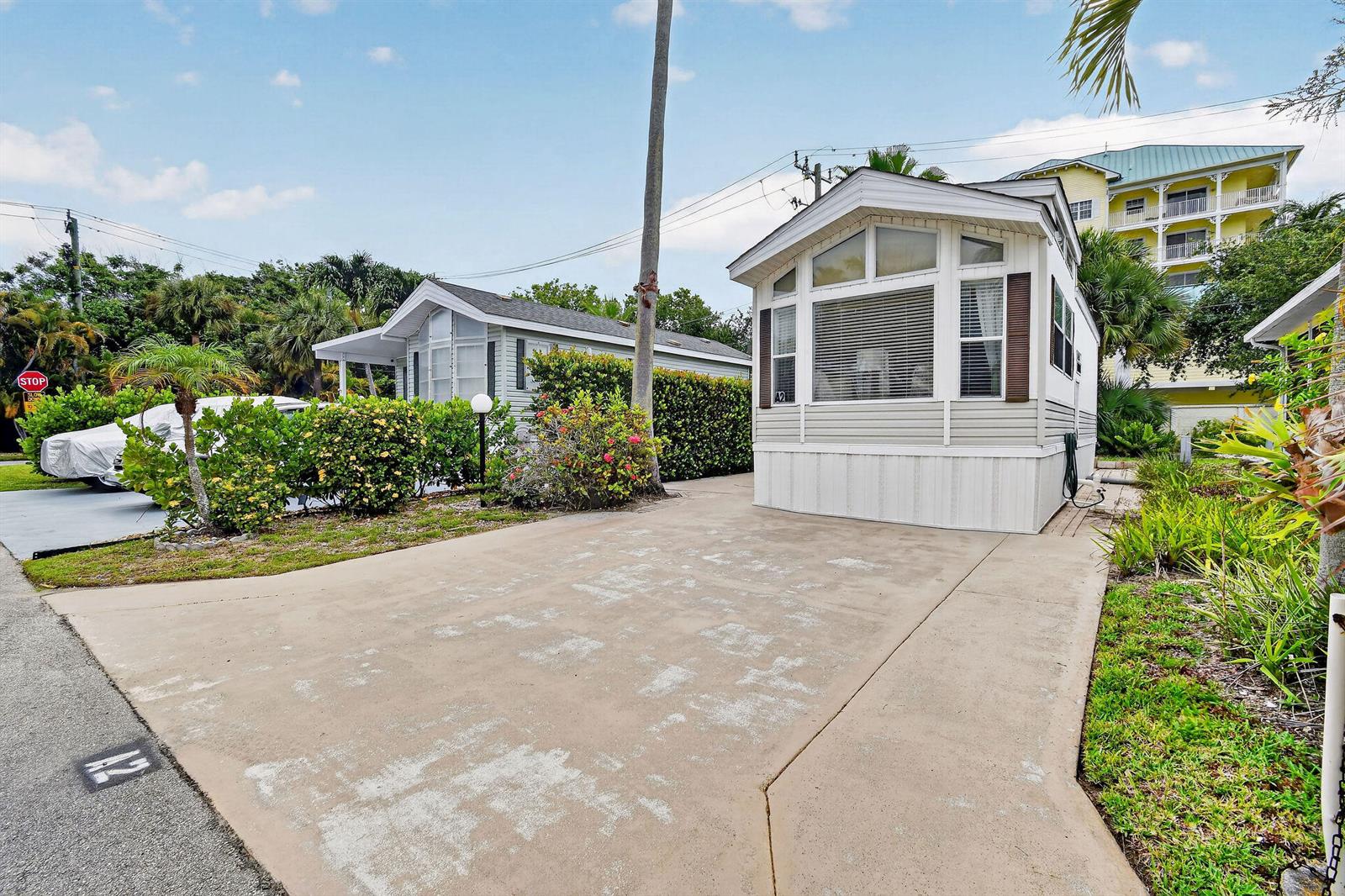 A light-colored mobile home sits on a concrete driveway with a palm tree nearby — 900 Juno Ocean Walk # 2, Juno Beach FL 33408, JUNO BEACH, FL