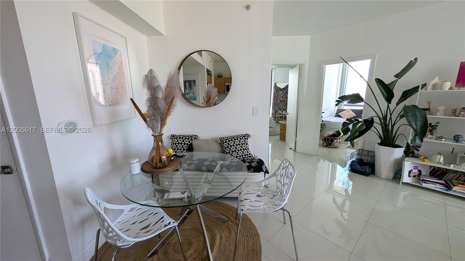 A dining area features a glass table, white chairs, and a round mirror on the wall — 350 S Miami Ave # 2813, Miami FL 33130, MIAMI, FL