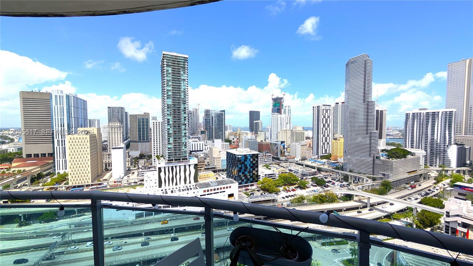 A high-angle view from a balcony overlooks a dense city skyline and highway interchange — 350 S Miami Ave # 2813, Miami FL 33130, MIAMI, FL