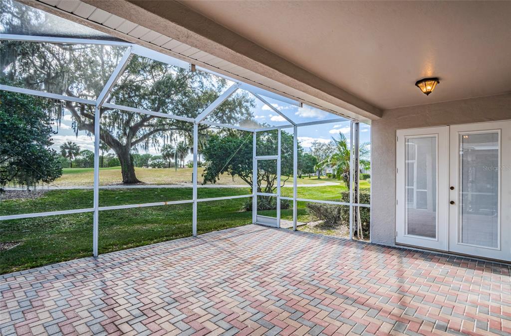 A screened-in patio with brick pavers overlooks a grassy yard with trees — 3254 STONEBRIDGE TRAIL, VALRICO, FL