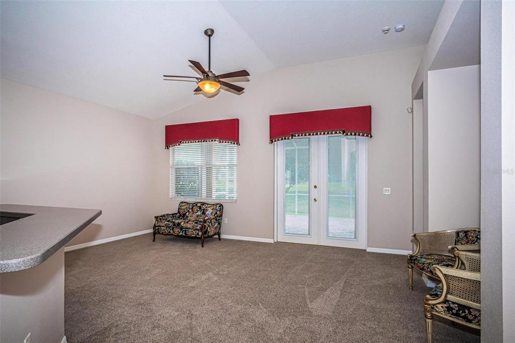 A living room with beige carpet, a ceiling fan, and an open kitchen with a counter — 3254 STONEBRIDGE TRAIL, VALRICO, FL