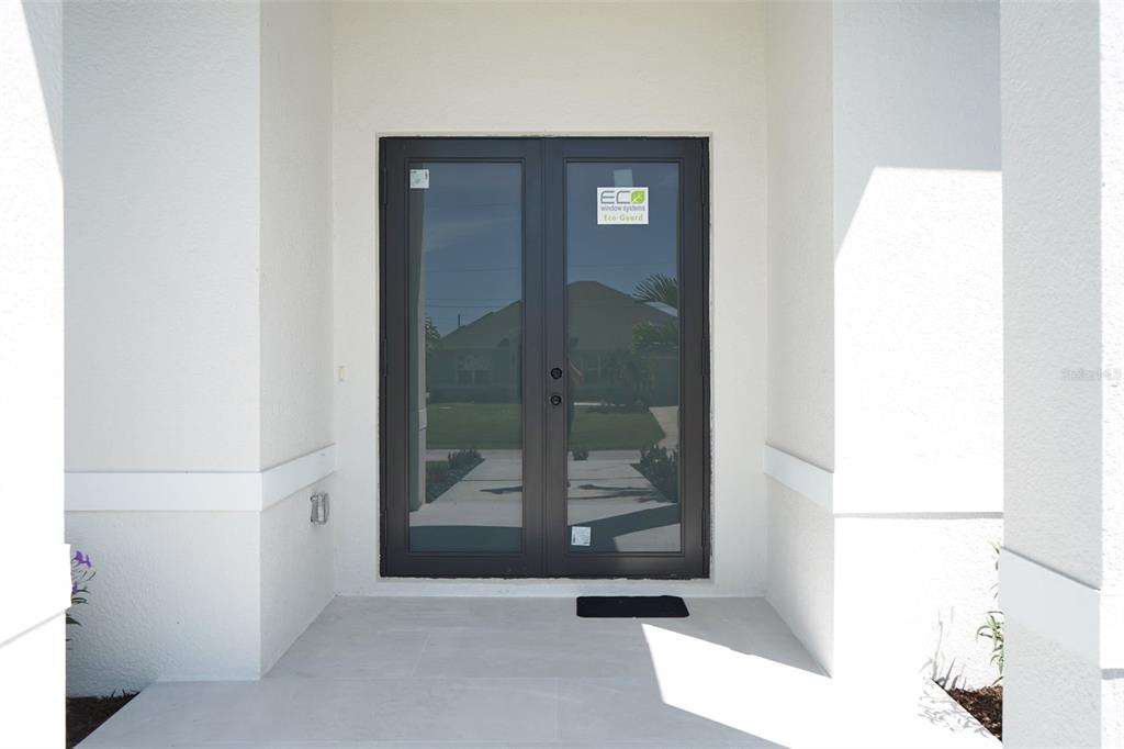A set of dark-framed glass double doors is centered on a white covered entryway — 14671 LILLIAN CIRCLE, PORT CHARLOTTE, FL