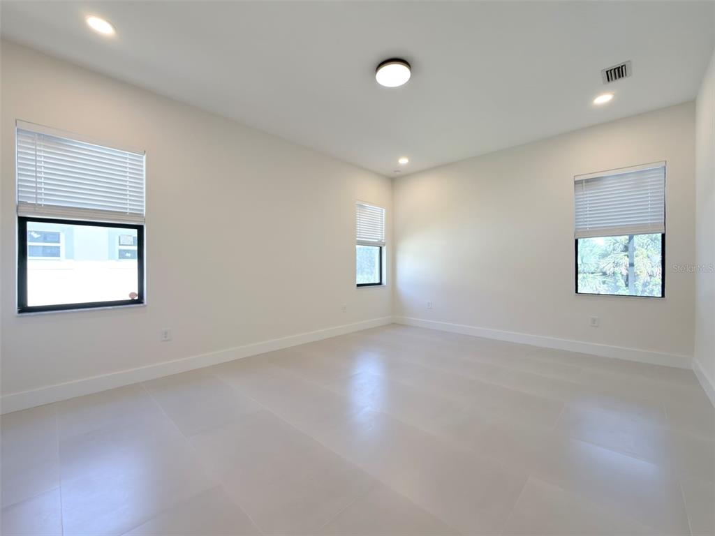 An empty room features white walls, light-colored tile flooring, and three windows with blinds — 14671 LILLIAN CIRCLE, PORT CHARLOTTE, FL