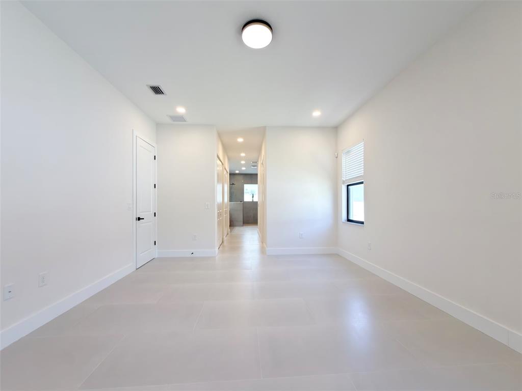 A bright, empty room with white walls, light tile flooring, and a recessed hallway — 14671 LILLIAN CIRCLE, PORT CHARLOTTE, FL