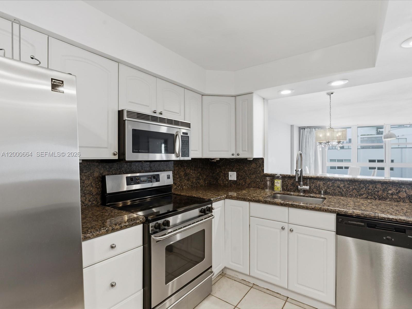 A kitchen features white cabinets, stainless steel appliances, and dark granite countertops — 1228 West Ave # 1506, Miami Beach FL 33139, MIAMI BEACH, FL