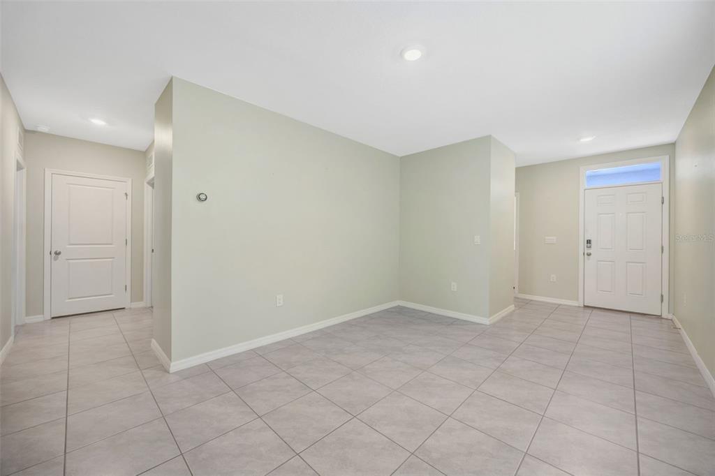 An interior view of a room with light green walls, light tile flooring, and a door — 33801 JASMINE STAR LOOP, WESLEY CHAPEL, FL