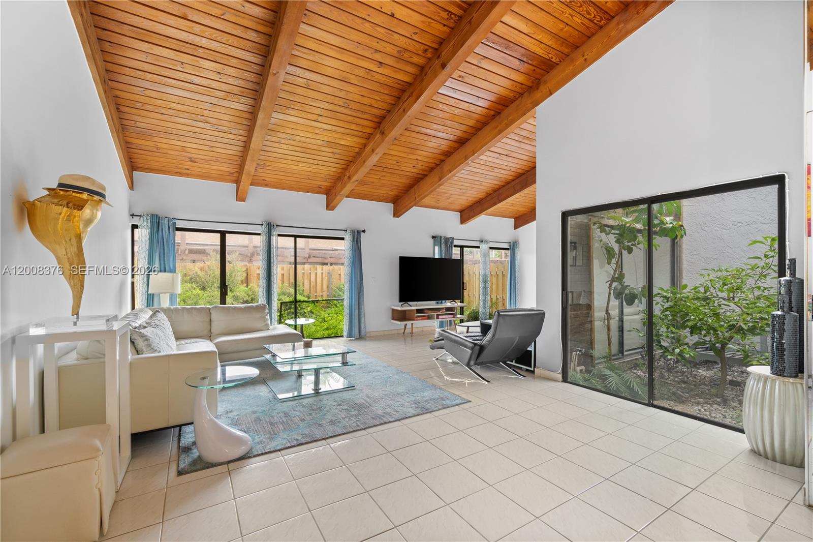 A living room features a vaulted wood-beam ceiling, white tile floors, and large glass doors — 2679 S Parkview Dr, Hallandale Beach FL 33009, HALLANDALE BEACH, FL