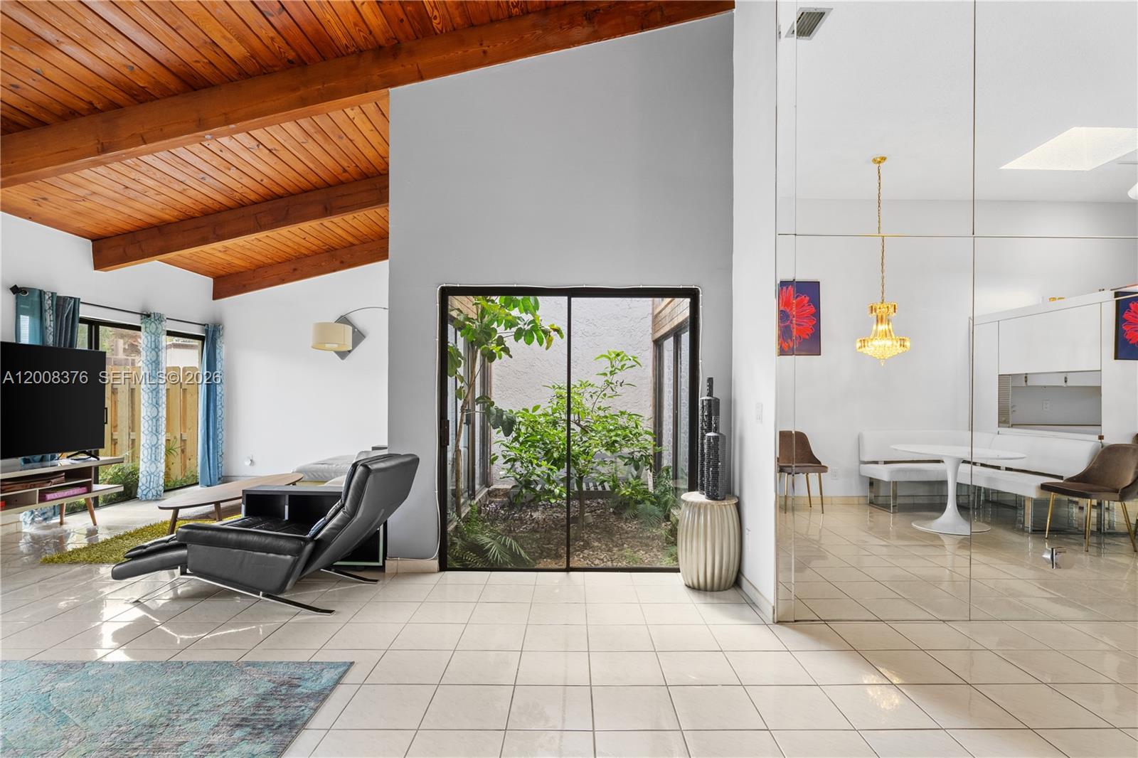 A living room with a vaulted wood ceiling, tiled floors, and an interior glass-enclosed courtyard — 2679 S Parkview Dr, Hallandale Beach FL 33009, HALLANDALE BEACH, FL