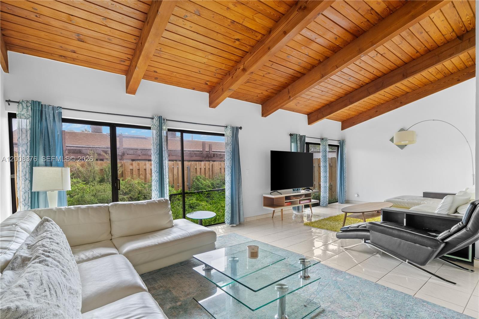 A living room features a vaulted wood-beam ceiling, white tile floors, and sliding glass doors — 2679 S Parkview Dr, Hallandale Beach FL 33009, HALLANDALE BEACH, FL