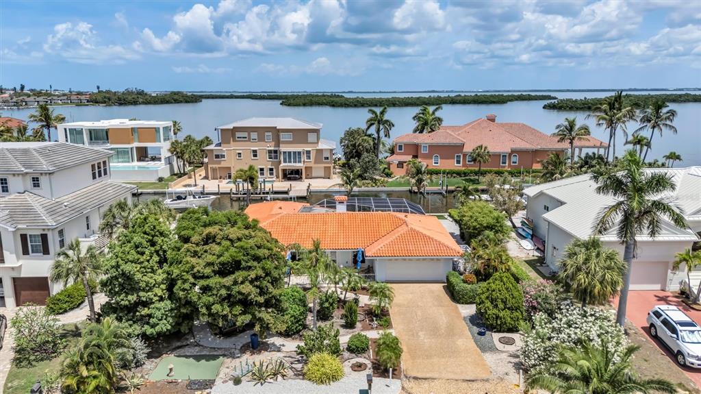 An aerial view shows a waterfront house with an orange tile roof and a driveway — 617 ROUNTREE DRIVE, LONGBOAT KEY, FL