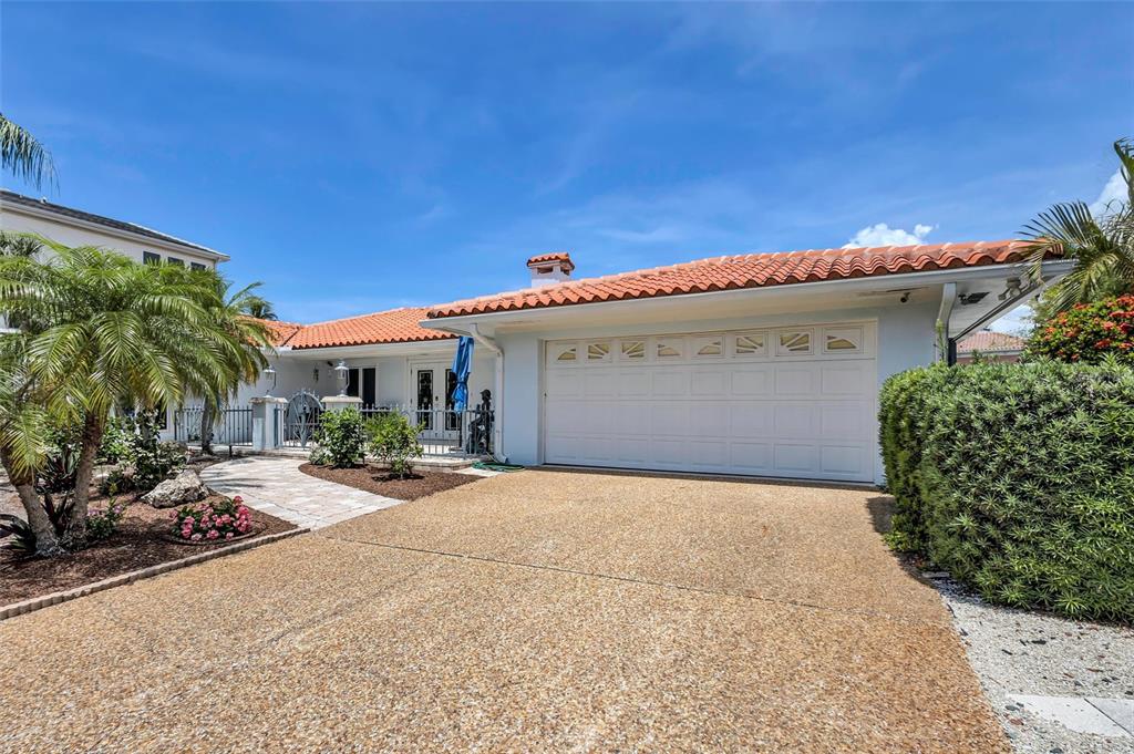 A single-story house with a white exterior, red tile roof, and a two-car garage — 617 ROUNTREE DRIVE, LONGBOAT KEY, FL