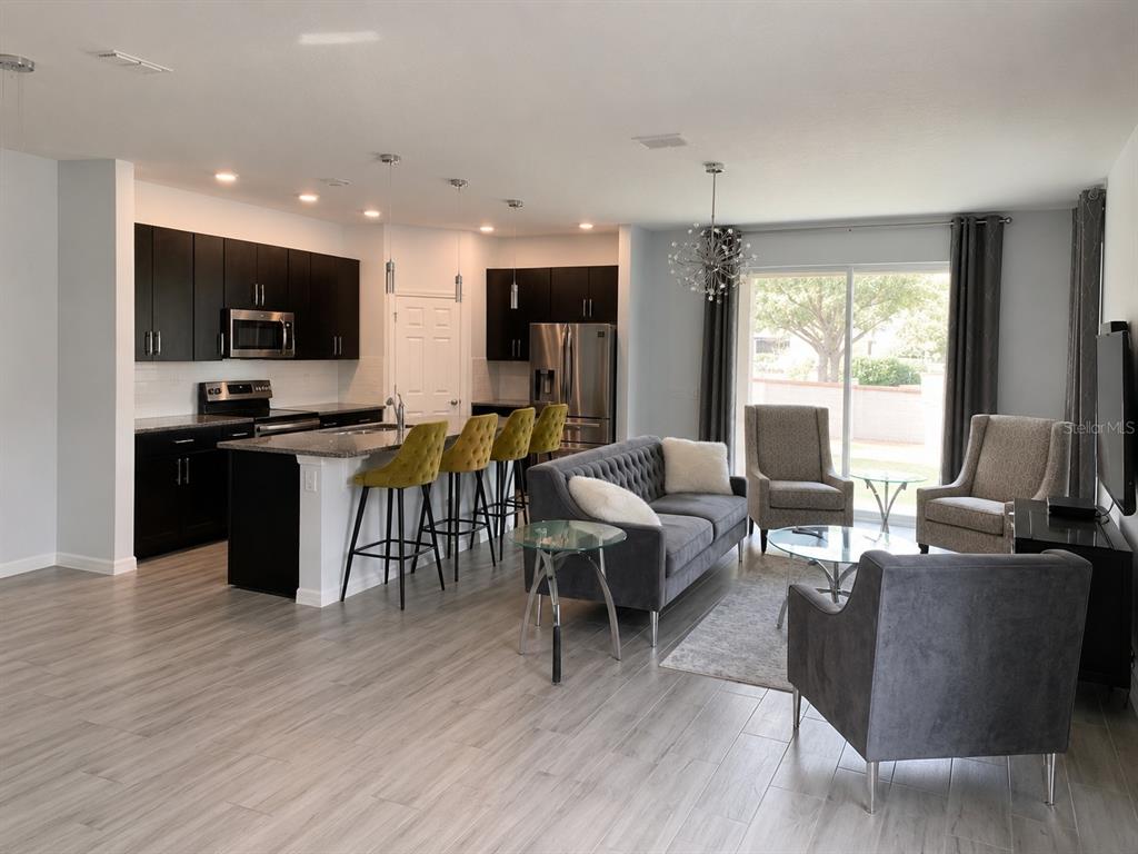 An open-concept kitchen and living area featuring dark cabinetry, a breakfast bar, and gray furniture — 290 ABERDEEN STREET, DAVENPORT, FL